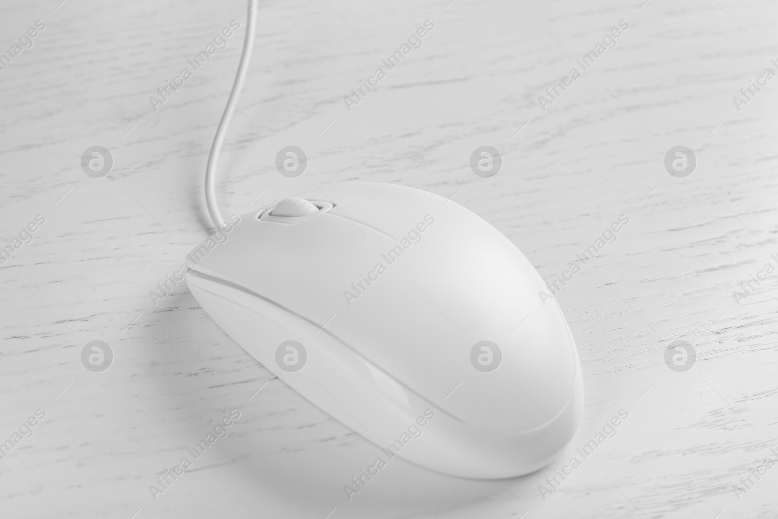 Photo of Modern wired optical mouse on white wooden table, closeup