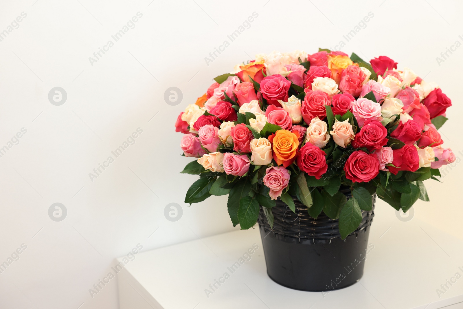 Photo of Bouquet of beautiful roses on white table, space for text