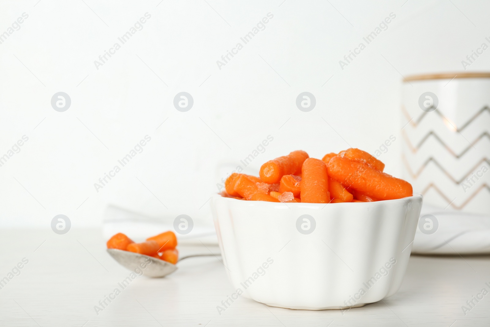 Photo of Bowl with frozen carrots on table. Vegetable preservation