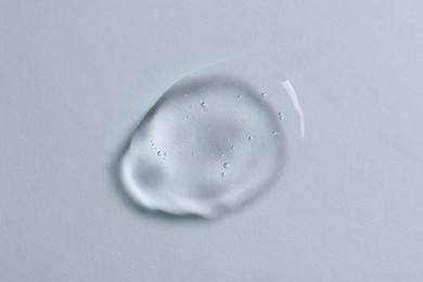 Photo of Drop of cosmetic oil on white background, top view