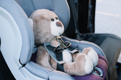 Teddy bear in child safety seat inside car