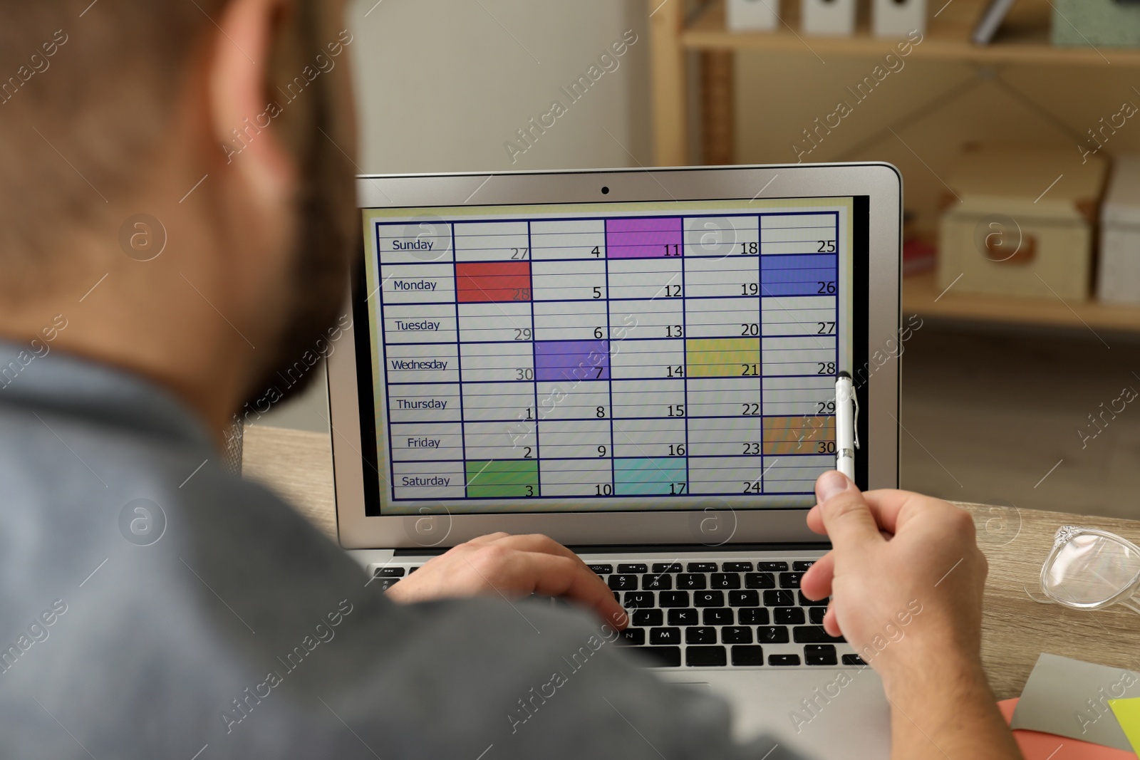 Photo of Young man using calendar app on laptop in office, closeup