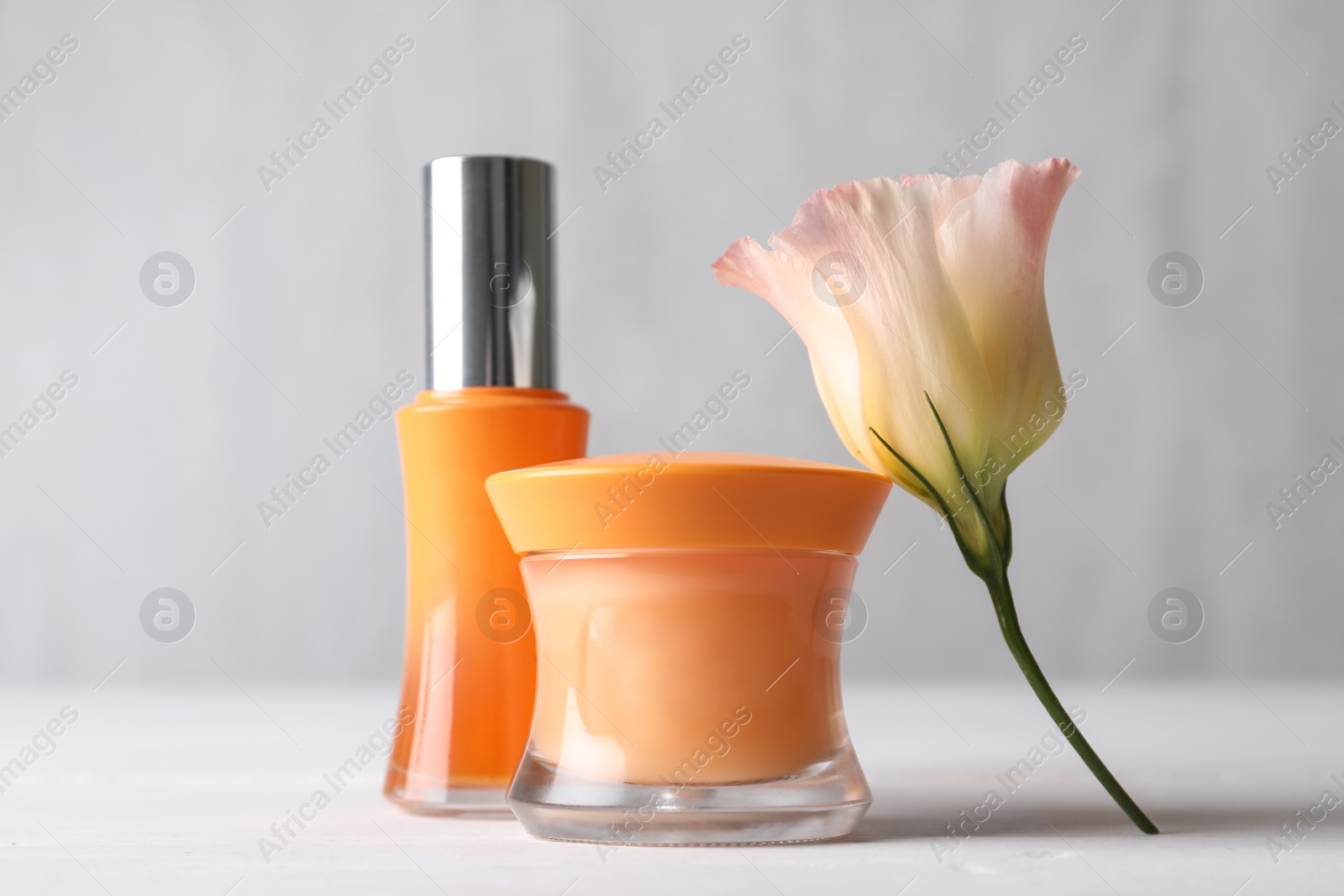 Photo of Set of luxury cosmetic products and beautiful flower on white table
