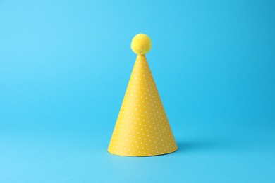 Photo of Yellow party hat on light blue background