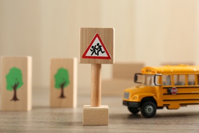Photo of Traffic sign Attention children crossing street and toy bus on wooden table. Passing driving license exam