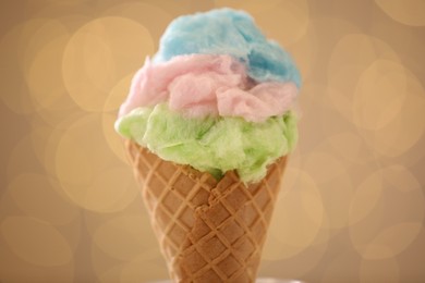 Photo of Sweet cotton candy in waffle cone against blurred lights, closeup