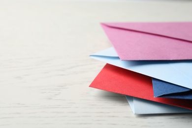 Colorful paper envelopes on white wooden background, closeup. Space for text