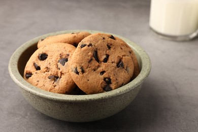 Photo of Delicious chocolate chip cookies and milk on grey table, closeup