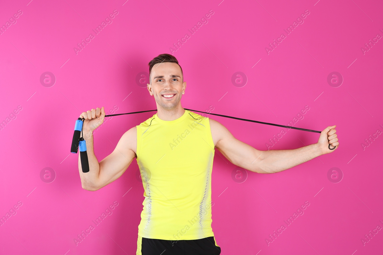 Photo of Portrait of young sportive man with jump rope on color background