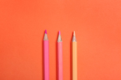 Photo of Color pencils on coral background, flat lay