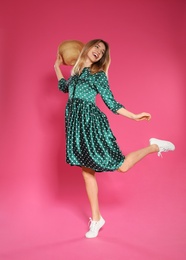 Full length portrait of emotional woman dancing on color background