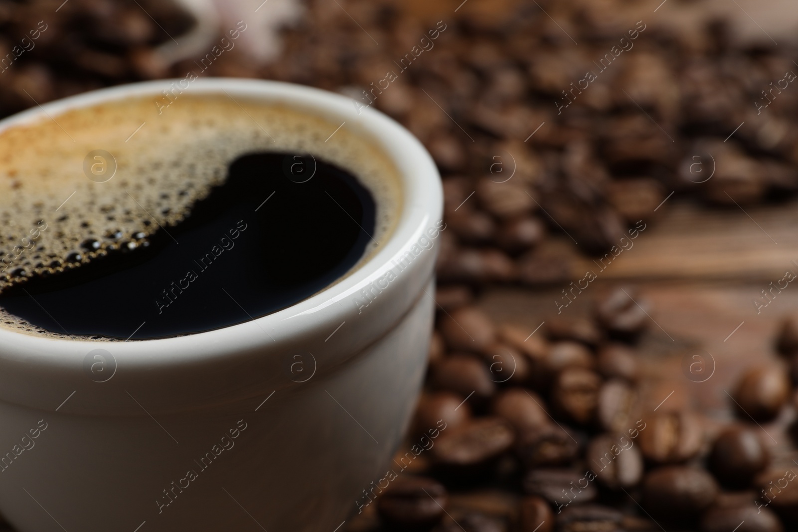 Photo of Cup of aromatic hot coffee and beans on table, closeup. Space for text