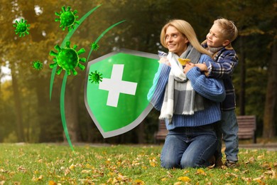 Image of Happy mother with her son on green grass in autumn park. Strong immunity - shield against viruses