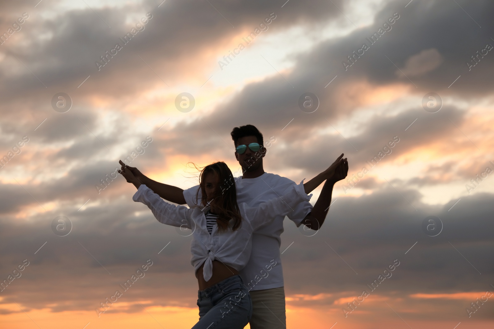 Photo of Happy couple dancing outdoors during beautiful sunset