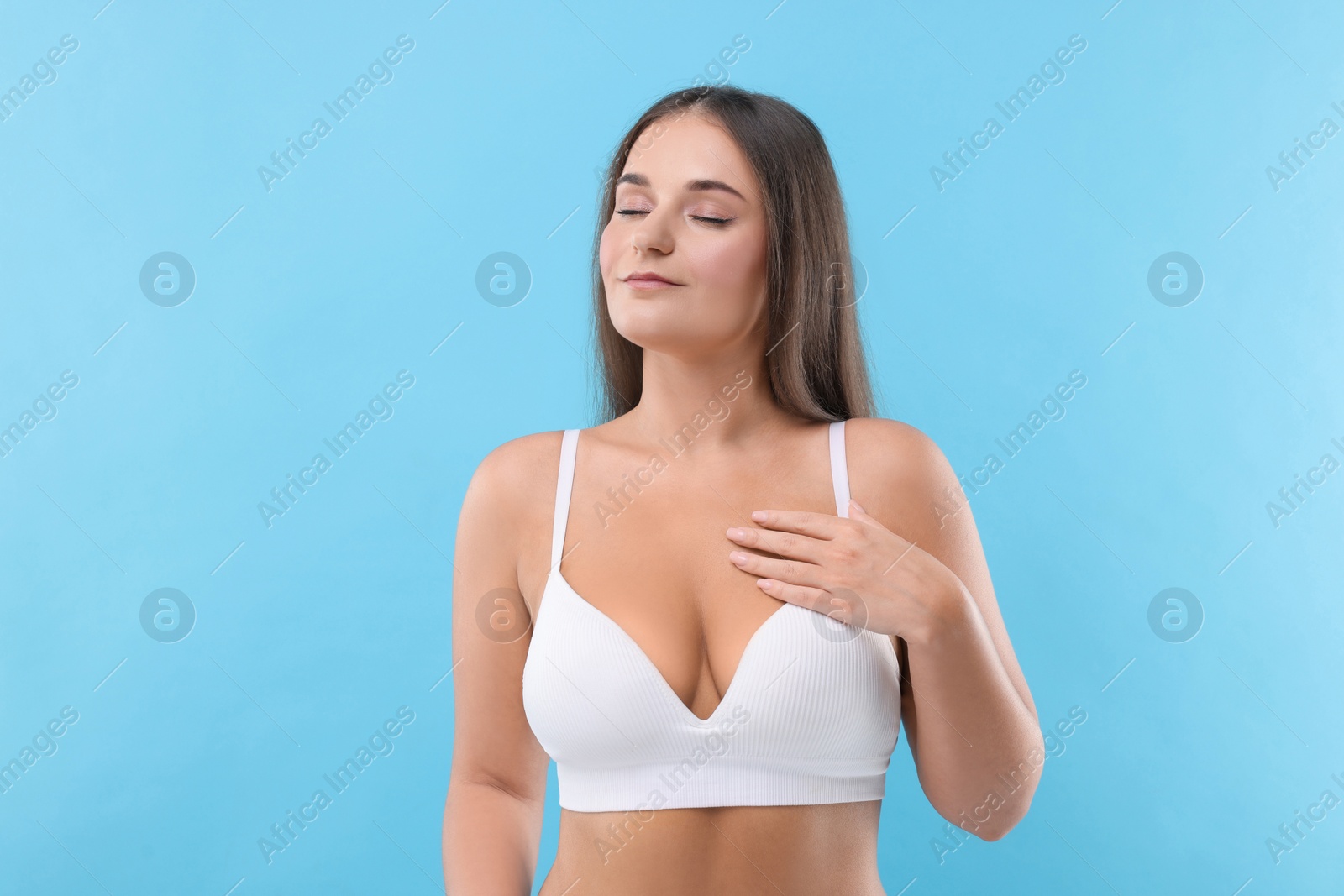 Photo of Portrait of young woman with beautiful breast on light blue background