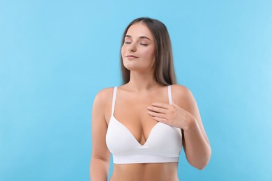 Photo of Portrait of young woman with beautiful breast on light blue background