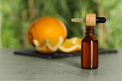 Bottle of citrus essential oil and pipette on grey table, space for text