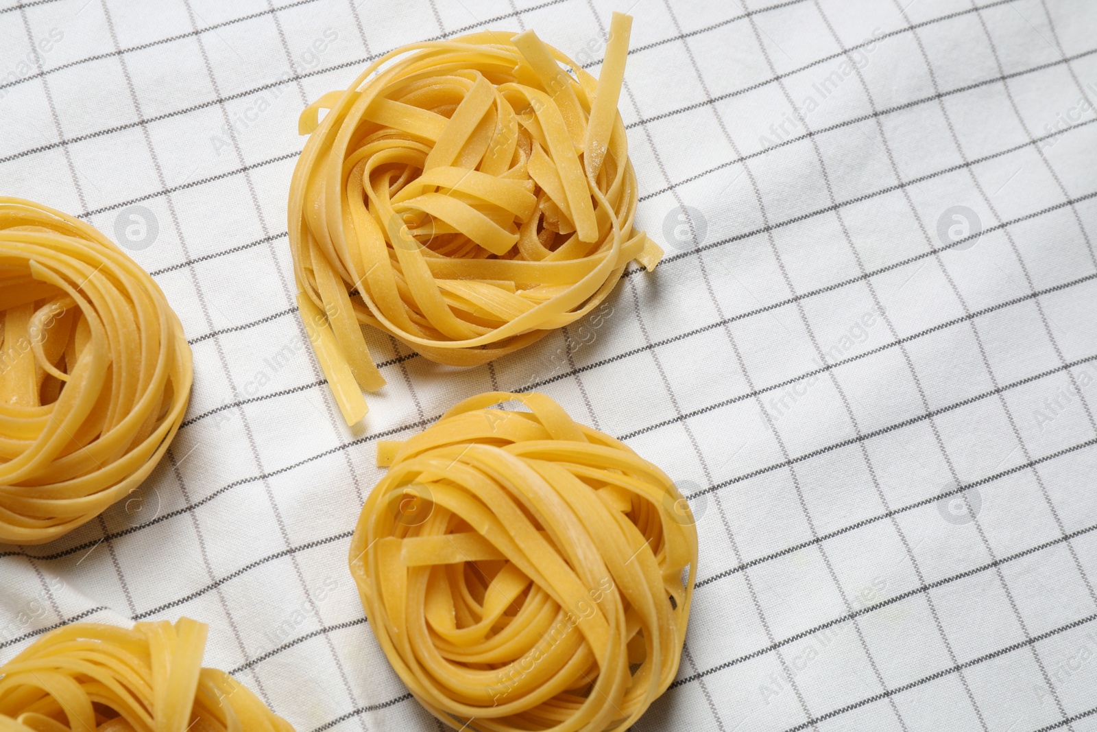 Photo of Tagliatelle pasta on white tablecloth, flat lay