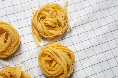 Photo of Tagliatelle pasta on white tablecloth, flat lay