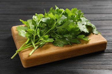 Photo of Fresh green cilantro and board on black wooden table