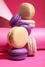 Delicious fresh colorful macarons and paper roll on pink background