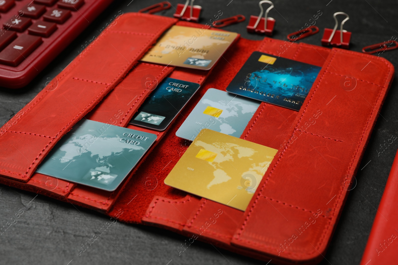 Photo of Credit cards in red wallet on black table, closeup