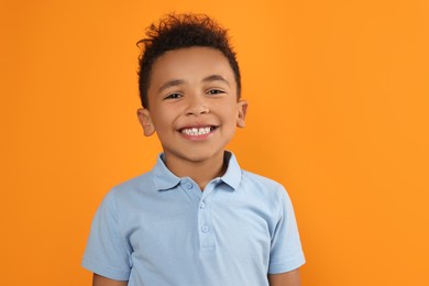 Photo of Portrait of cute African-American boy on orange background
