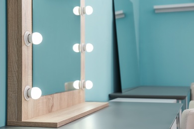 Photo of Makeup mirror with light bulbs on table in dressing room