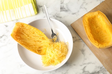 Cooked spaghetti squash and fork in dish on table, top view