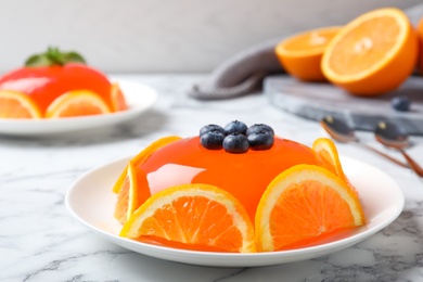 Photo of Delicious fresh jelly with orange slices and blueberries on marble table