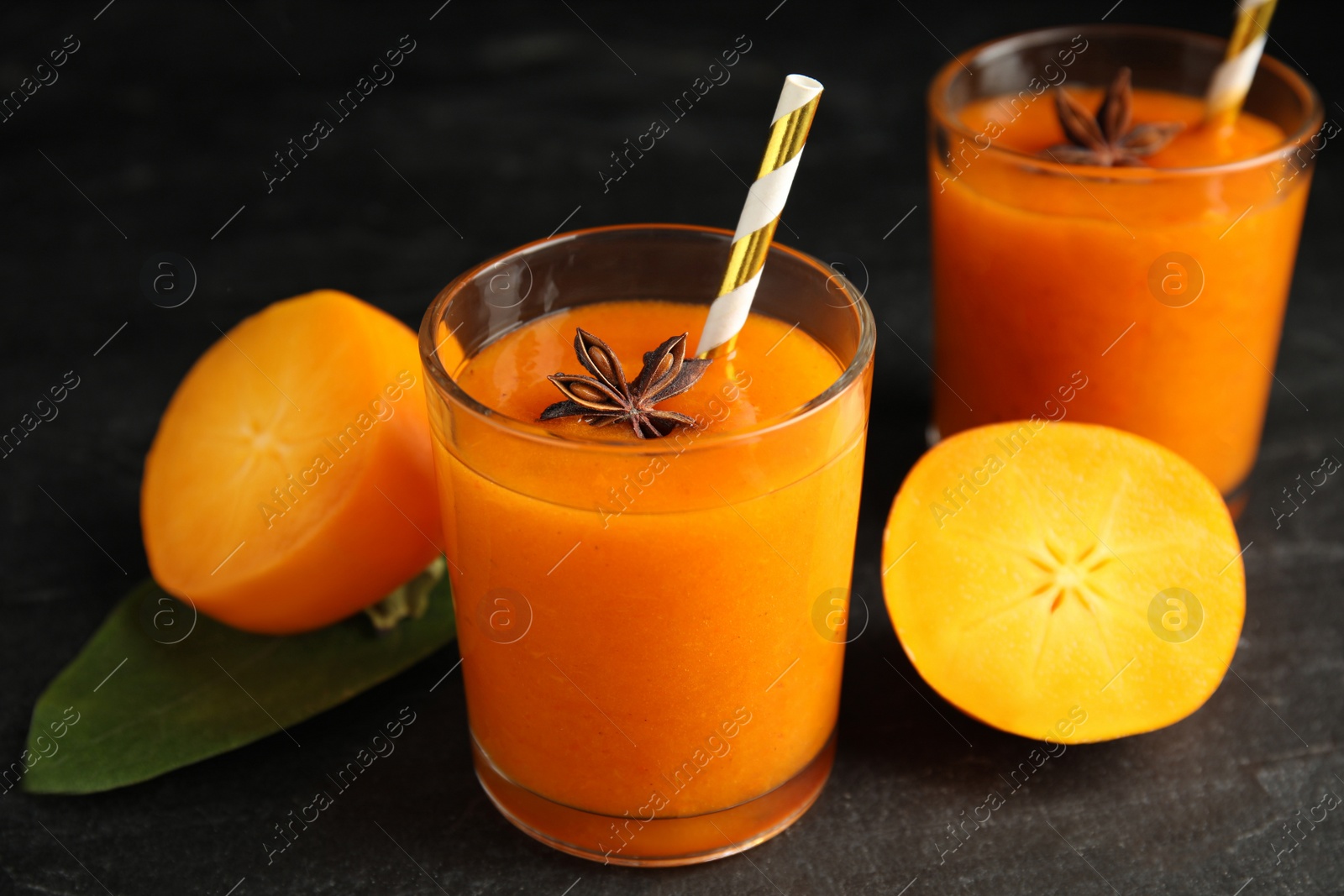 Photo of Tasty persimmon smoothie with anise and fresh fruits on black table