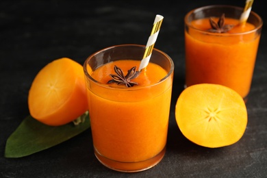 Photo of Tasty persimmon smoothie with anise and fresh fruits on black table