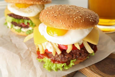 Tasty burgers with fried egg on wooden board