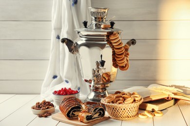 Traditional Russian samovar and treats on white wooden table