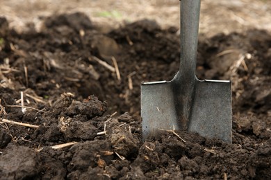 Shovel in soil outdoors, space for text