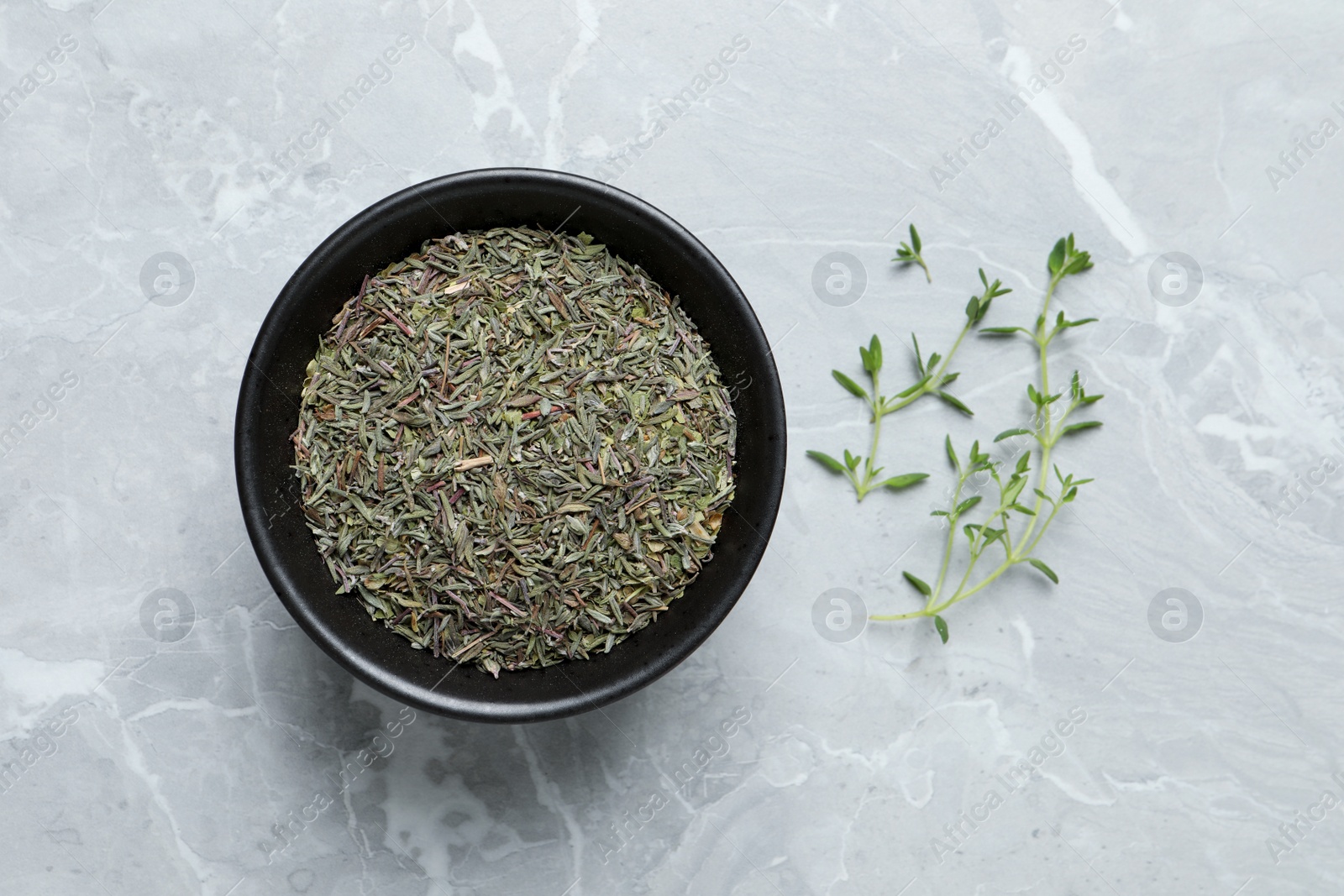 Photo of Bowl with dried thyme and fresh twigs on light table, flat lay