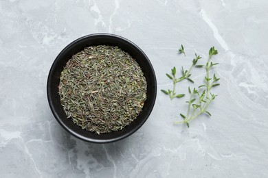 Bowl with dried thyme and fresh twigs on light table, flat lay