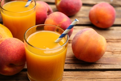Photo of Natural peach juice and fresh fruits on wooden table, closeup