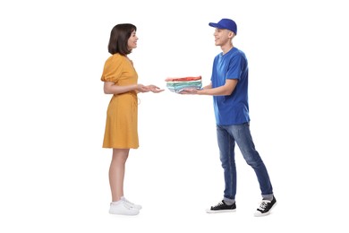 Dry-cleaning delivery. Courier giving folded clothes to woman on white background