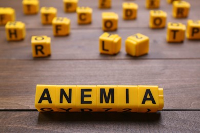 Photo of Word Anemia made with yellow cubes on wooden table