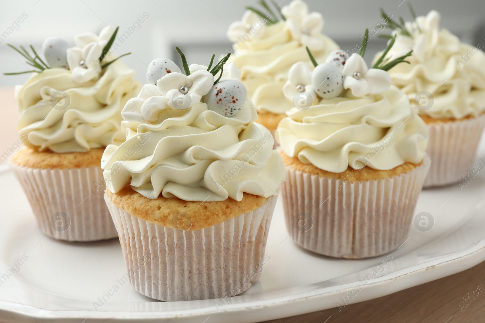 Photo of Tasty Easter cupcakes with vanilla cream on table, closeup