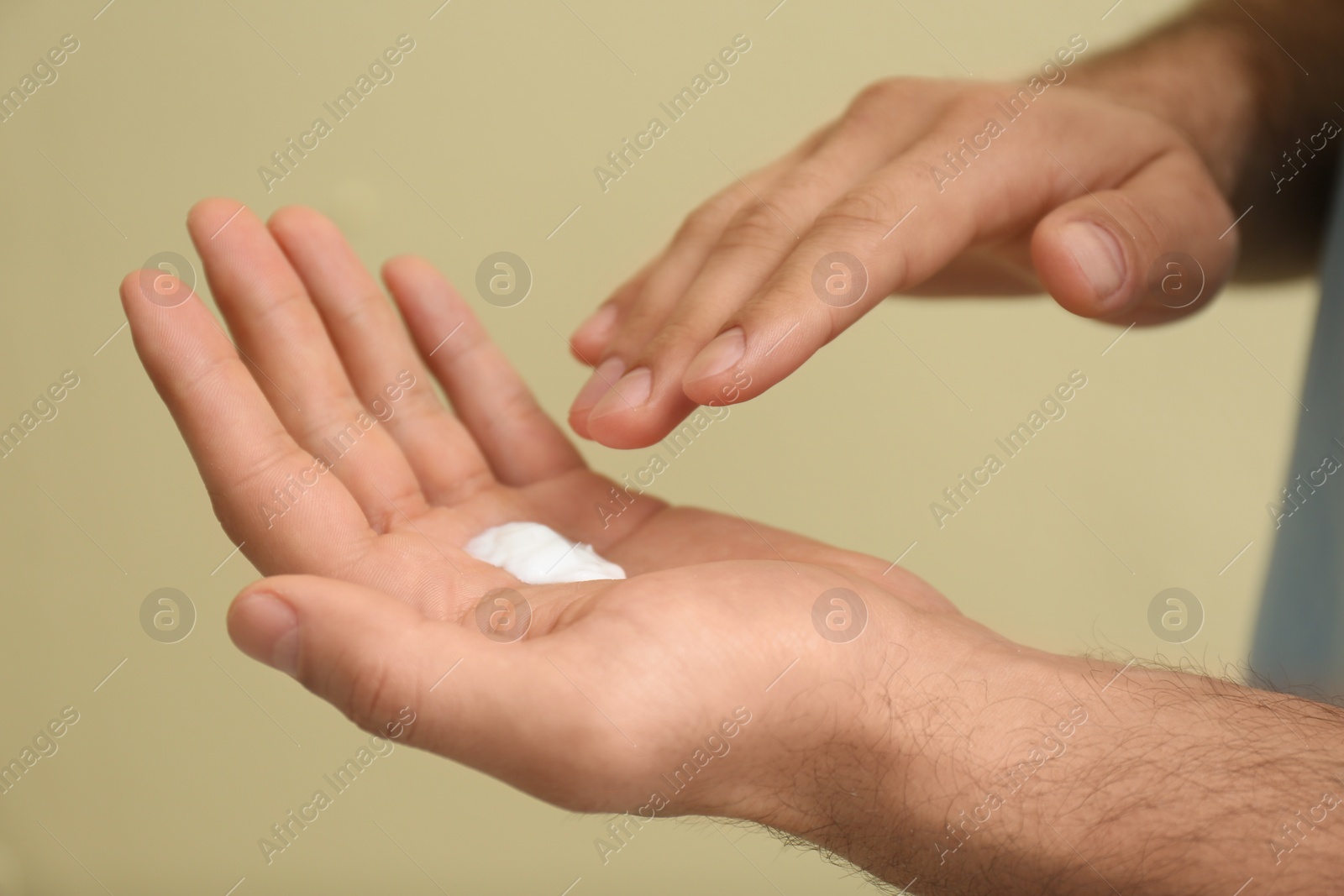 Photo of Man with cream on hand against yellow background, closeup