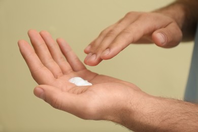 Photo of Man with cream on hand against yellow background, closeup