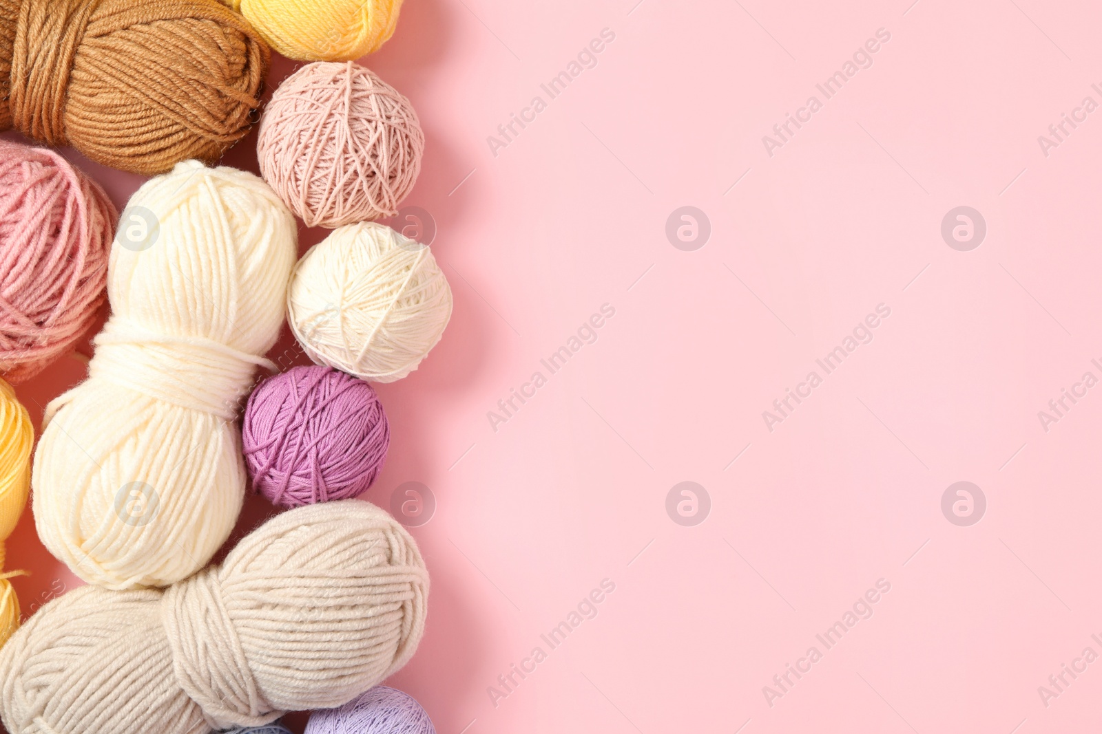 Photo of Soft colorful woolen yarns on pink background, flat lay. Space for text