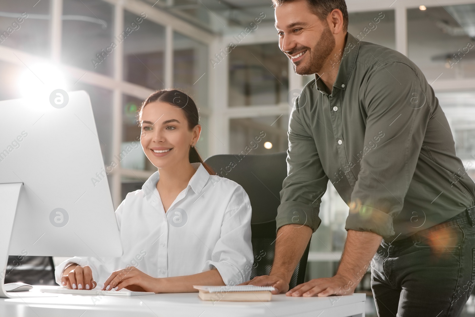 Photo of Colleagues working on computer at desk in office