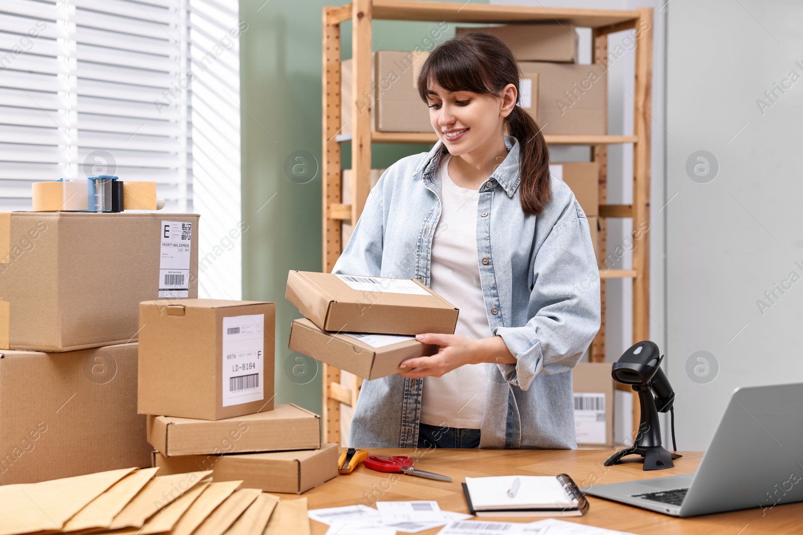 Photo of Parcel packing. Post office worker with parcels at wooden table indoors