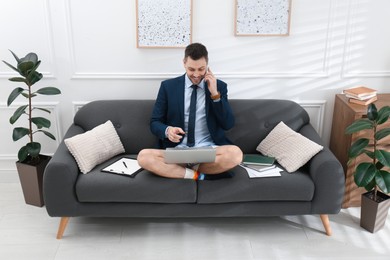 Businessman in shirt and underwear talking on phone during video call at home