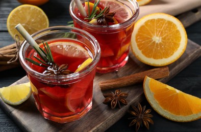 Photo of Aromatic punch drink and ingredients on black wooden table