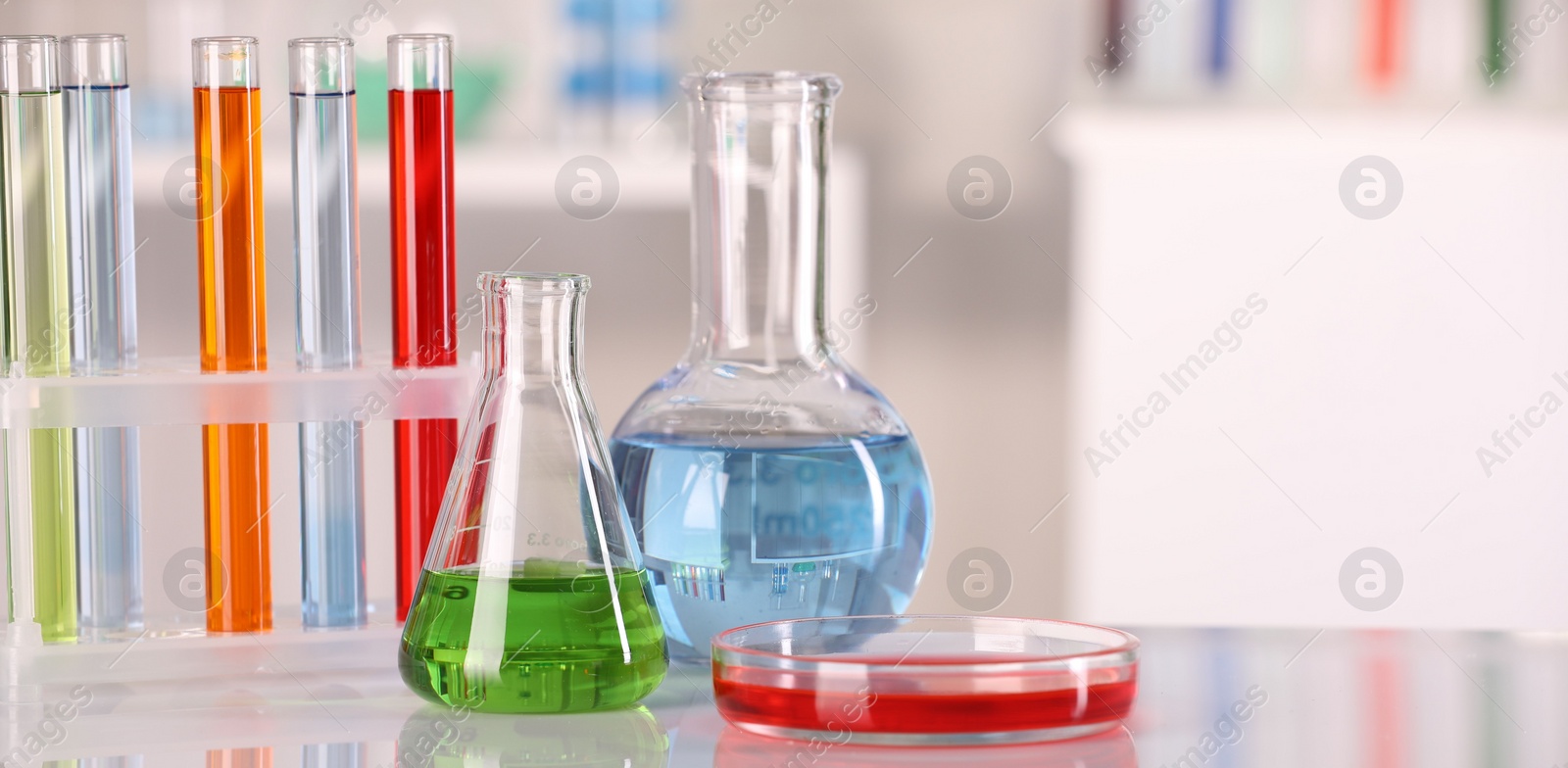 Photo of Laboratory analysis. Different glassware with liquids on white table against blurred background. Space for text