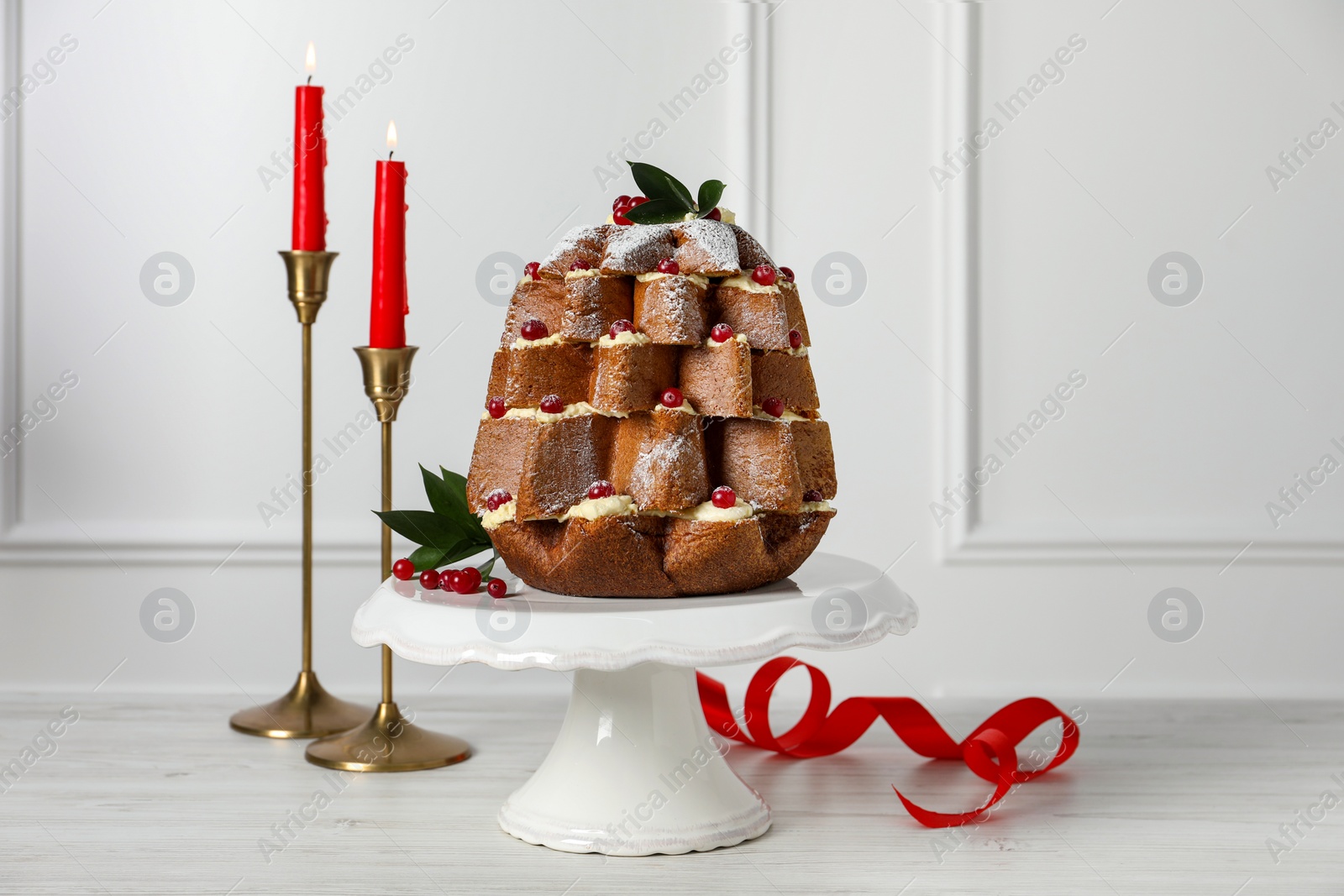 Photo of Delicious Pandoro Christmas tree cake with powdered sugar and berries near festive decor on white table